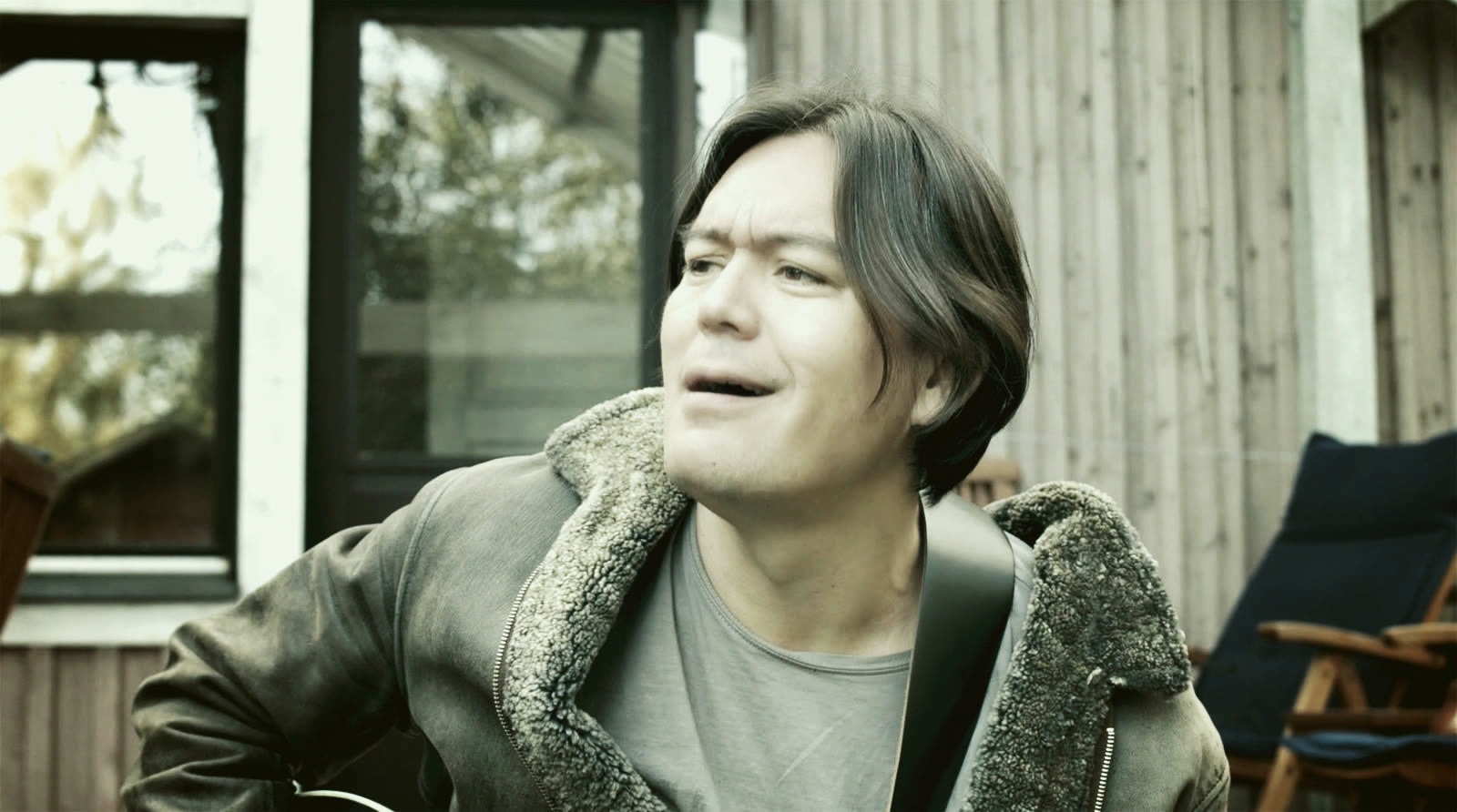 A singer in a leather jacket on a terrace. Still from the music video Hengitän.