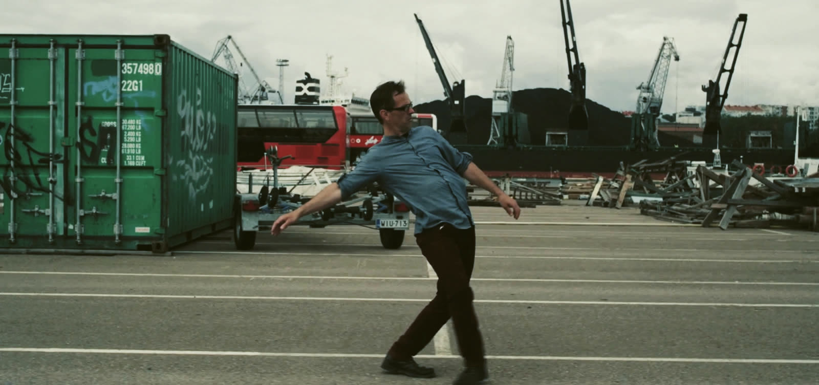 A man dancing in a harbour area. Scene from The Gig.