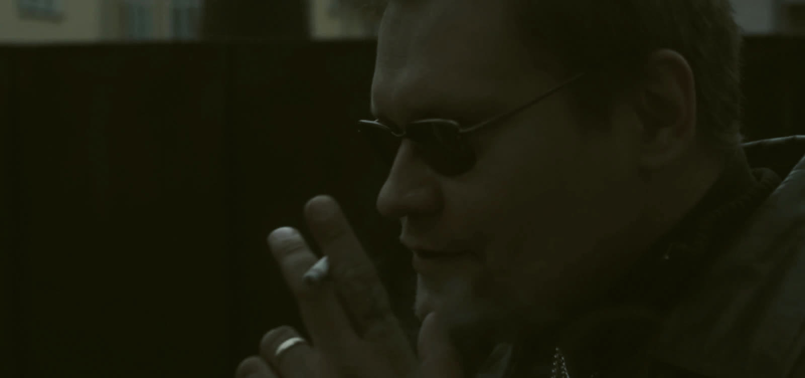 A man in sunglasses holding a cigarette. Scene from How We Became Friends.